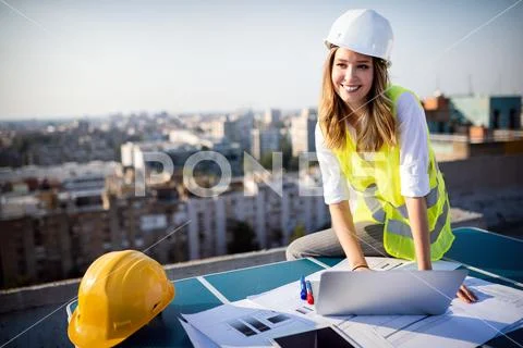 Young female construction specialist engineer reviewing blueprints at Stock Photos