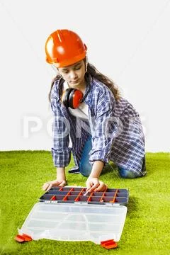 A young female construction worker chooses a tool for work in a box. Building Stock Photos