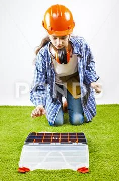 A young female construction worker chooses a tool for work in a box. Building Stock Photos