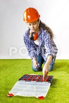 A young female construction worker chooses a tool for work in a box. Building Stock Photos