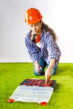 A young female construction worker chooses a tool for work in a box. Building Stock Photos