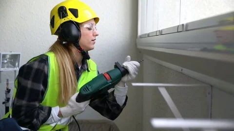 Young Female construction worker drilling concrete wall with a drill and smiling Stock Footage 74069835