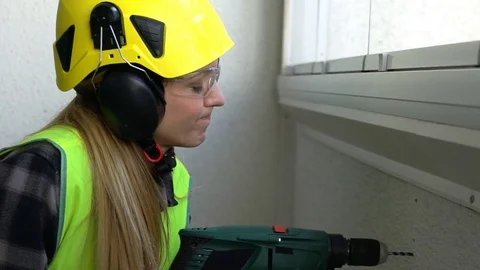 Young Female construction worker drilling concrete wall with a drill and smiling Stock Footage 74072321