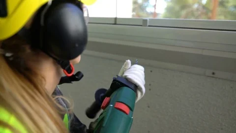Young Female construction worker drilling concrete wall with a drill and smiling Stock Footage 74072873