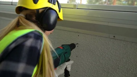 Young Female construction worker drilling concrete wall with a drill and smiling Stock Footage 74073052