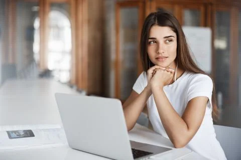 Young female copywriter using a notebook computer to write an article thinking Stock Photos