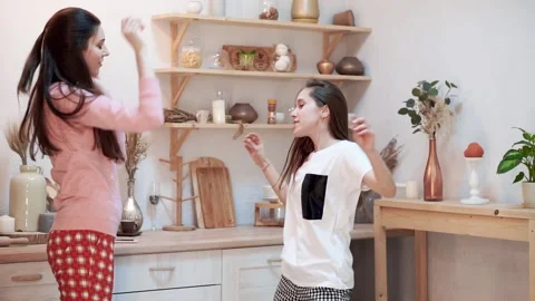 Young female couple dancing in kitchen in pajamas Stock Footage 176337072
