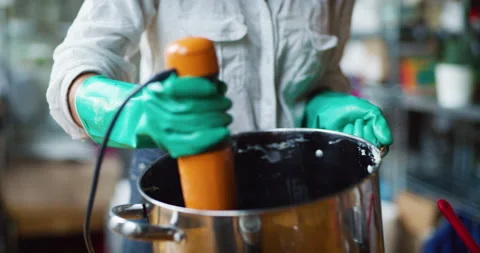 Young female craftsman using a blender to mix together ingredients for making so Stock Footage 199457225