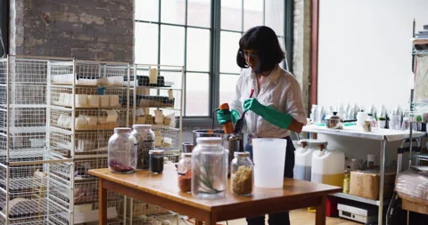 Young female craftsman using a blender to mix together ingredients for making so Stock Footage 199457729