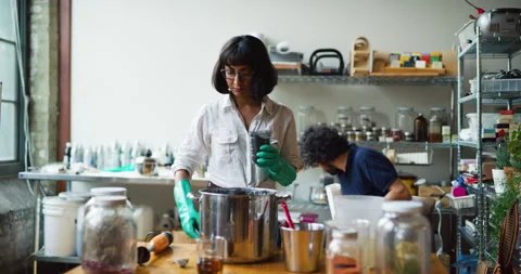 Young female craftsman using a blender to mix together ingredients for making so Stock Footage 199458705