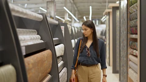 Young female customer looking at large assortment of wallpapers for home Stock Footage 157129494