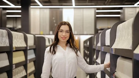 Young female customer looking at large assortment of wallpapers for home Stock Footage 281247774