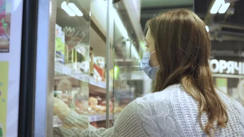 A young female customer reads the composition of the drink on the juice bottle Stock Footage 169650940