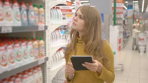 Young female customer using tablet computer while choosing household chemistry Stock Footage 75274646