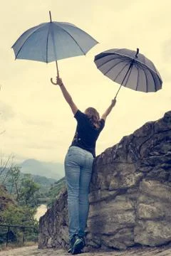 Young female dancing in the rain using pair of umbrellas. Stock Photos