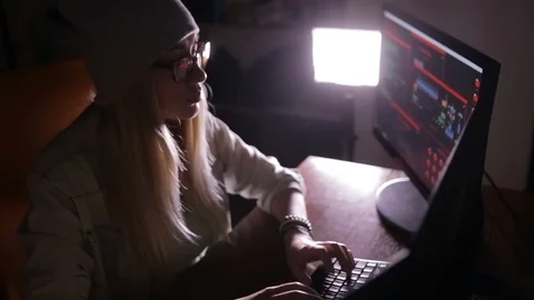 Young female in dark inputting data, computer codes, breaking security system Stockbeeldmateriaal 71271026