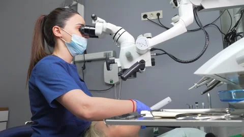 Young female dentist treating root canals using microscope at dental clinic. Stock Footage 239724541