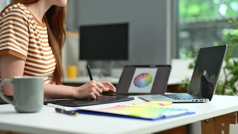 Young female designer using pen tablet and color palette while working in a.. Stock Footage 312437302