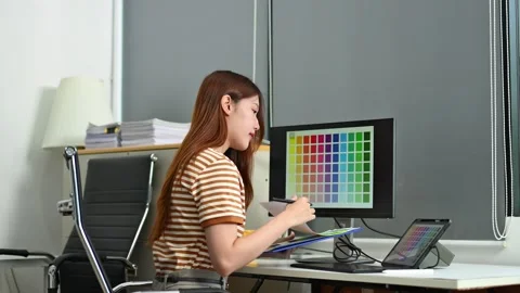 Young female designer using pen tablet and color palette while working in a.. 스톡 동영상 312437537