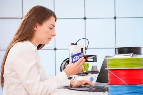 Young female designer working on a prototype device on a 3D printer Stock Photos