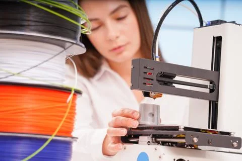 Young female designer working on a prototype device on a 3D printer Stock Photos