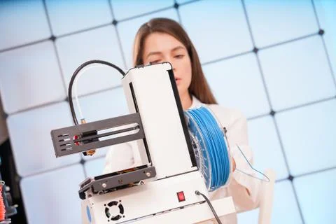 Young female designer working on a prototype device on a 3D printer Stock Photos