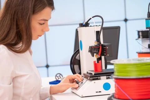 Young female designer working on a prototype device on a 3D printer Stock Photos