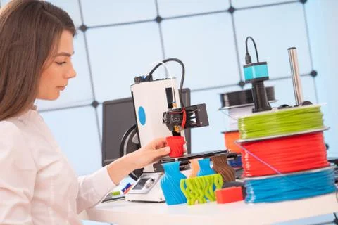 Young female designer working on a prototype device on a 3D printer Stock Photos