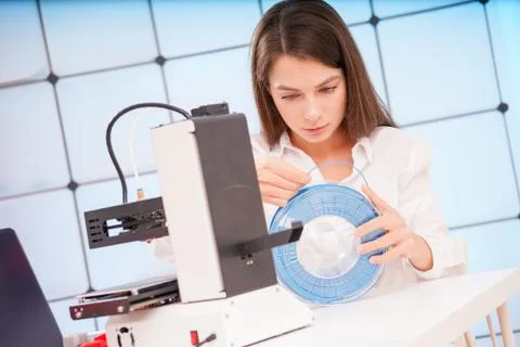 Young female designer working on a prototype device on a 3D printer Foto stock