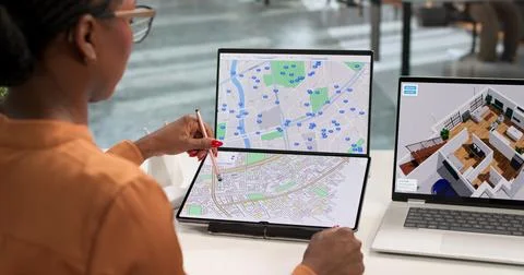 Young Female Developer Analyzes Urban Land Plans On Laptop For City Project. Stock Photos