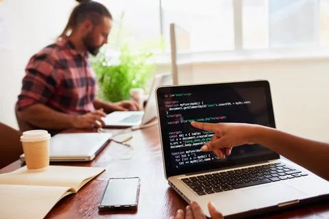 Young female developer points finger to laptop screen with javascript code Stock Photos