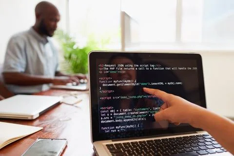 Young female developer points finger to laptop screen with javascript code Foto stock