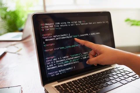Young female developer points finger to laptop screen with javascript code 스톡 사진