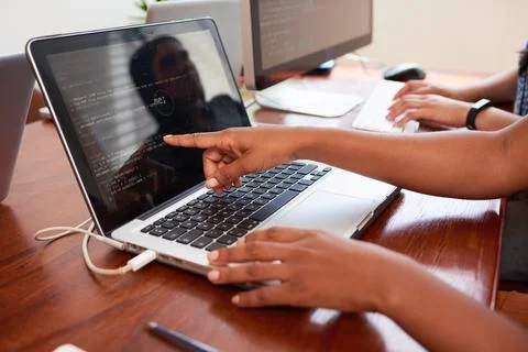 Young female developer points finger to laptop screen with javascript code Stock Photos