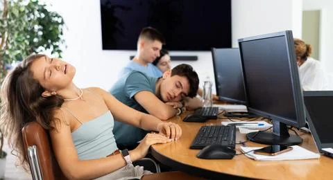 Young female developer tired after workday napping near computer Stock Photos