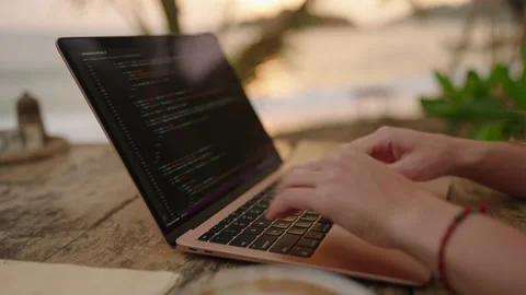Young female developer working on laptop by the ocean. Woman freelancer coding Stock Footage 234809803
