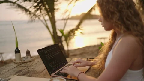 Young female developer working on laptop by the ocean. Woman freelancer coding Stock Footage 236819289