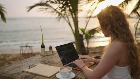 Young female developer working on laptop by the ocean. Woman freelancer coding Stock Footage 237581537