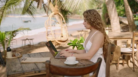 Young female developer working on laptop by the ocean. Woman freelancer coding Stock Footage 239522609