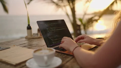 Young female developer working on laptop by the ocean. Woman freelancer coding Stock Footage 240278929