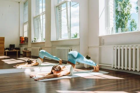 Young female do complex of stretching yoga exercises on floor in light sunny Stock Photos