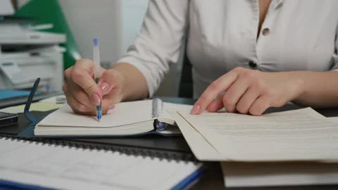 Young female doctor knocks on table with pen and starts writing in notebook 스톡 동영상 195812518