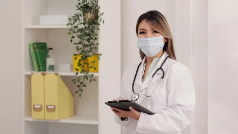 Young female doctor using tablet in hand and posing while standing in clinic Stock Footage 162235975