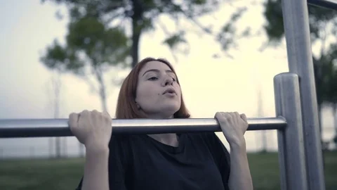 Young female doing pull ups using bars at the park Stock Footage 80946808