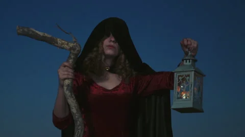 Young female dressed as a witch posing with a stick and lamp Stock Footage 55825544