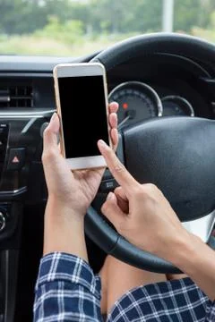 Young female driver using touch screen smartphone in a car. Stock Photos