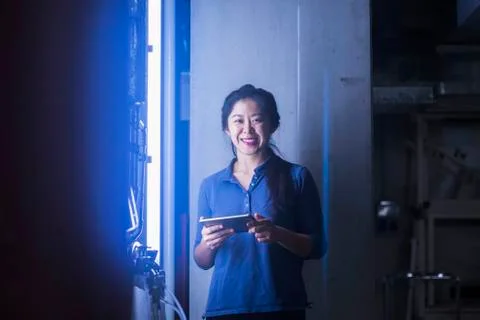 Young female engineer using digital tablet and smiling in an industrial plant 스톡 사진