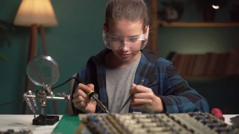 Young female engineer using soldering iron to join chips and wires. Robotics and Stock Footage 253002093