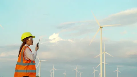 Young female engineer using walkie talkie to checking system against wind turbin Stock Footage 157782863