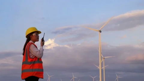 Young female engineer using walkie-talkie to checking system against wind turbin Video stock 157857599